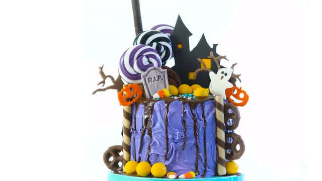On trend Halloween candyland fantasy novelty drip cake on white background.
