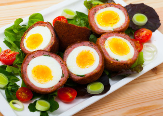 Fototapeta na wymiar Scotch eggs with tomatoes, greens and leek, traditional Scottish cuisine