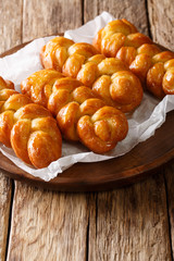 Traditional Koeksisters South African sticky donut sweet, sticky, crunchy and drenched in syrup, laced with cinnamon, lemon and ginger close-up on the table. vertical