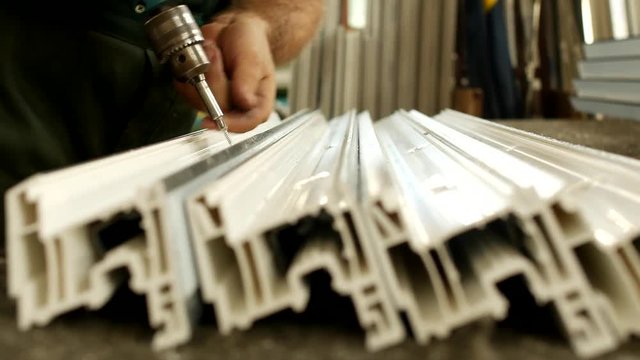 Manufacturing windows pvc, male worker twists screws in the profile pvc for window manufacturing, shop and windows, screwdriver