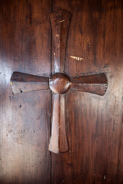 Croce in legno scolpita su portone in legno