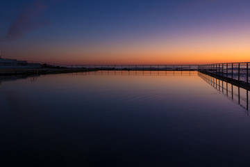 Dawn sky reflection in a seaside coastal pool. Early morning, twilight colours.