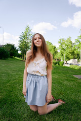 Pretty young girl sitting next to bike in grass and having a rest