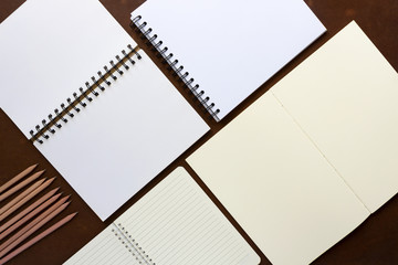 You can sketch or write text on white paper with a pencil placed on a brown wooden desk.