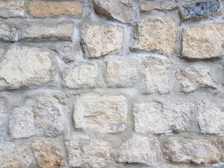 Ancient medieval stone masonry. Texture of a fragment of a wall of an old structure. A background for design and creative work. Decoration and exterior decoration of the building. Construction works.