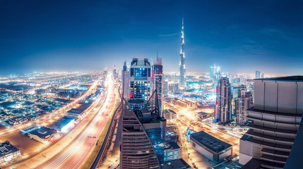 Obraz premium Spektakularna miejska panorama z kolorowymi iluminacjami miasta. Widok z lotu ptaka na autostrady i drapacze chmur w Dubaju, w Zjednoczonych Emiratach Arabskich.