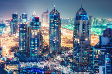 Obraz premium Malownicza nocna panorama dużego nowoczesnego miasta. Widok z lotu ptaka na drapacze chmur i autostrady w Dubai Marina, Zjednoczone Emiraty Arabskie. Wielobarwny tło podróży.