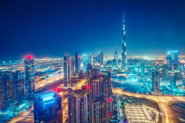 Fototapeta na wymiar Colourful nightime skyline of a big modern city. Dubai, United Arab Emirates. Aerial view on highways and skyscrapers.