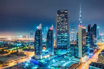 Poster Spectaculaire stedelijke skyline met kleurrijke stadsverlichting. Luchtfoto op snelwegen en wolkenkrabbers van Dubai, Verenigde Arabische Emiraten. © Funny Studio