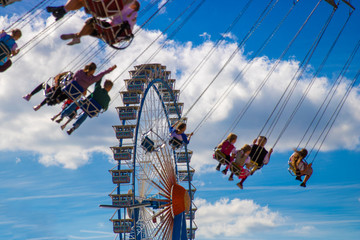Ferris wheel and carousel in motion blur at at the biggest folk festival of the world - the...