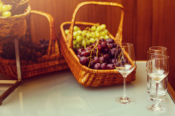 Green grapes bunch on kitchen table . Glasses with red wine and white wine .