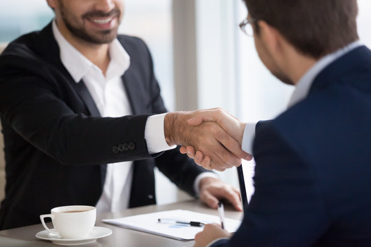 Close up of happy businessmen shaking hands after successful negotiations, partners or CEO handshaking closing corporate deal, two men managers thanking each other for office meeting. Human resources
