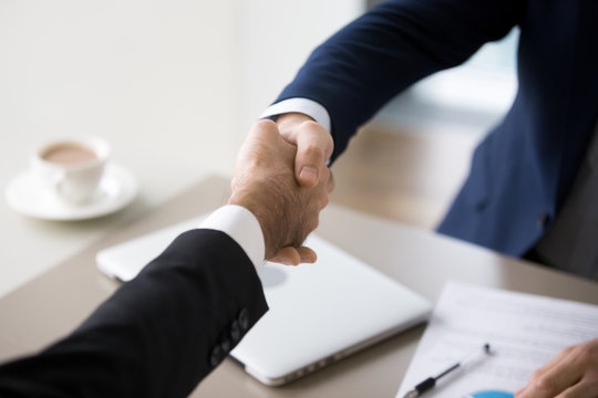 Close up of male businessmen handshake after successful negotiations in office, CEO shake hand of colleague during meeting, partners greeting or thanking for talk. Concept of cooperation, partnership