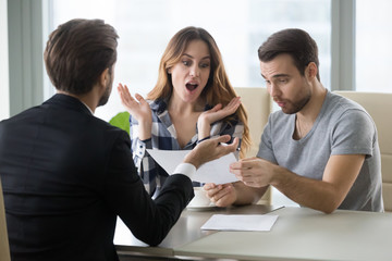 Amazed couple surprised by unbelievable offer made by realtor or agent, excited millennial man and woman shocked by great opportunity or good deal buying first home together or purchasing apartment