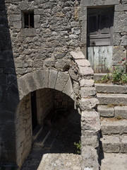 Grauer Hauseingang und Kellereingang mit Steintreppe in der Sonne, Frankreich