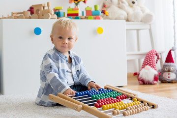 Cute little baby boy, playing with abacus at home