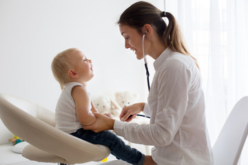 Pediatrician examining baby boy. Doctor using stethoscope to listen to kid
