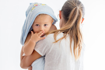 Mother holding little baby wrapped in towel after bath.