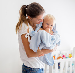 Mother holding little baby wrapped in towel after bath © Tomsickova
