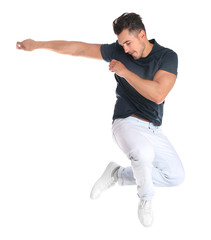 Young man in stylish jeans jumping on white background