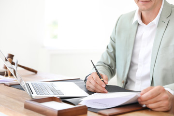 Male notary signing document at table in office, closeup