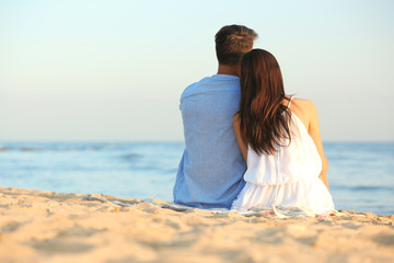 Fototapeta na wymiar Happy young couple sitting together on beach