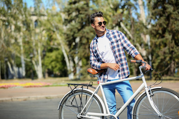 Handsome young hipster man with bicycle outdoors