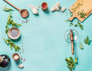 Food background frame with various herbs, seasoning and spices, cooking spoon and cutting board on...