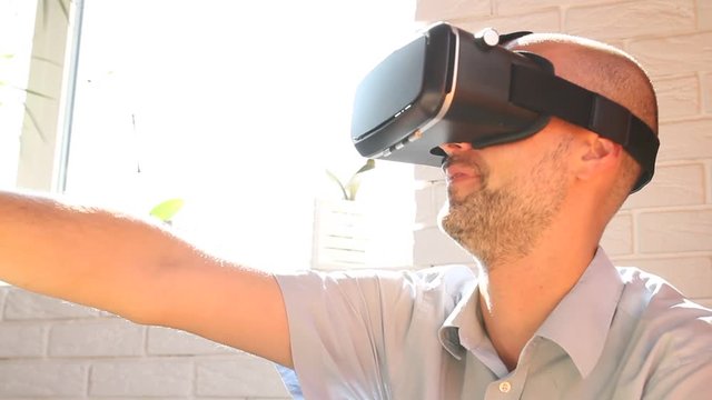 Man using virtual reality headset at office. Bearded man uses VR headset display for game