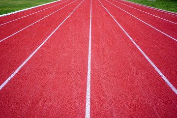 red rubber running racetrack with white lines in outdoor stadium