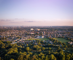 Sunrise aerial view of houses in London above a London housing estate next to countryside and farm land. Fields and community housing can be seen in the foreground