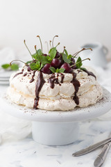 Pavlova cake with chocolate topping and cherries on a white background