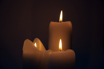 Trzy palące się świece na ciemnym tle
