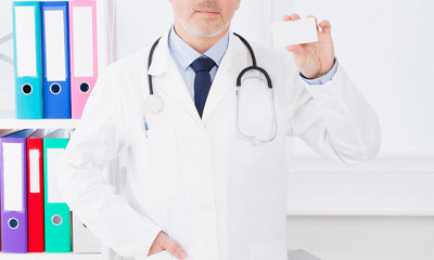 Doctor hold business card in clinic, medical insurance, man in white uniform. Copy space
