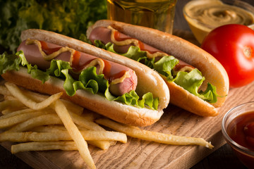 Photo of barbecue grilled hot dog with yellow mustard and ketchup on wooden background. Hot dog...