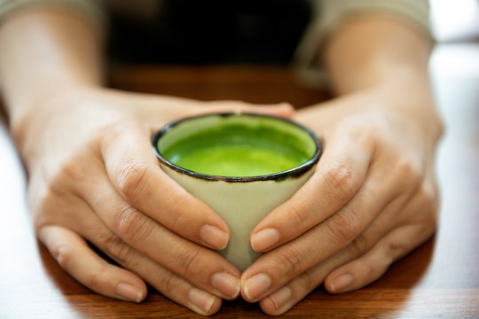 Hand holding a glass of green tea Japan.