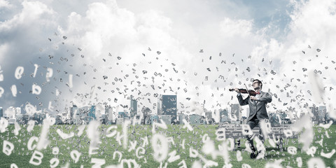 Handsome violinist in park on wooden bench and symbols fly aroun