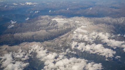 Flying over the European Alps during summer season. Landscape at the glaciers. Aerial view from the airplane window