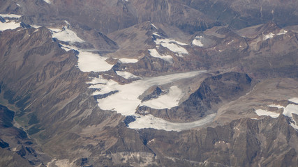 Flying over the European Alps during summer season. Landscape at the glaciers. Aerial view from the airplane window