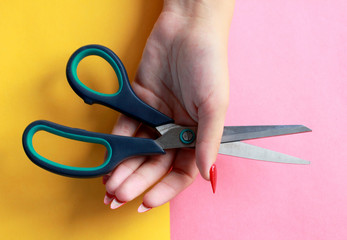 Fun minimal concept. Woman hands with scissors. Top view. Pastel colours background. Trendy colors.