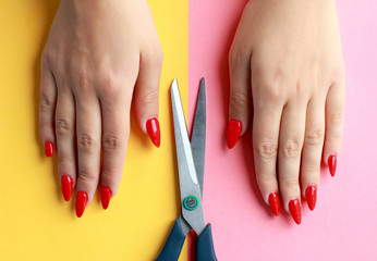 Fun minimal concept. Woman hands with scissors. Top view. Pastel colours background. Trendy colors.