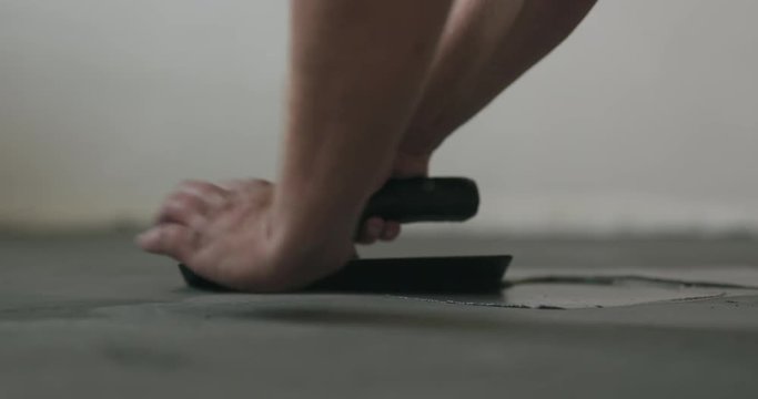 Slow motion closeup male worker applying micro concrete on the floor with a trowel
