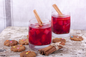 Два стакана с алкогольным напитком. Палочки корицы и печенье имбирное 