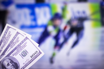 Money dollars on the background of a TV on which show skating sports, sports betting, racing skates dollars