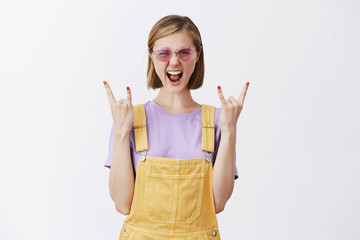 Rock n roll lives forever. Portrait of amazed excited beautiful female with fair hair in sunglasses...