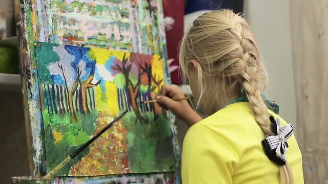 Little girl painter paints a picture