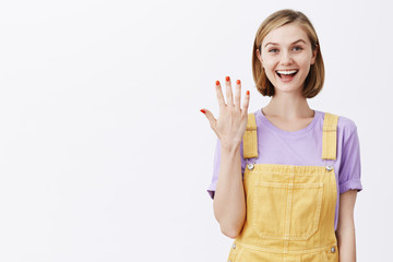 Obraz premium Look at my new manicure. Charming feminine carefree woman with fair short hair, showing number five with palms and smiling with interest and happiness, talking casually to camera, making video blog