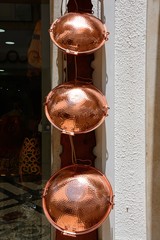 Traditional Portuguese copper cataplana cooking pots hanging outside a shop in the city centre, Faro, Algarve, Portugal.