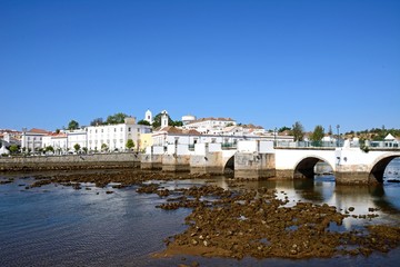 View of the Roman bridge (Ponte Romano) and Gilao river with town buildings to the rear, Tavira, Portugal.