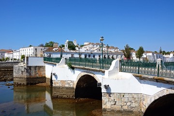 View of the Roman bridge (Ponte Romano) and Gilao river with town buildings to the rear, Tavira, Portugal. © arenaphotouk